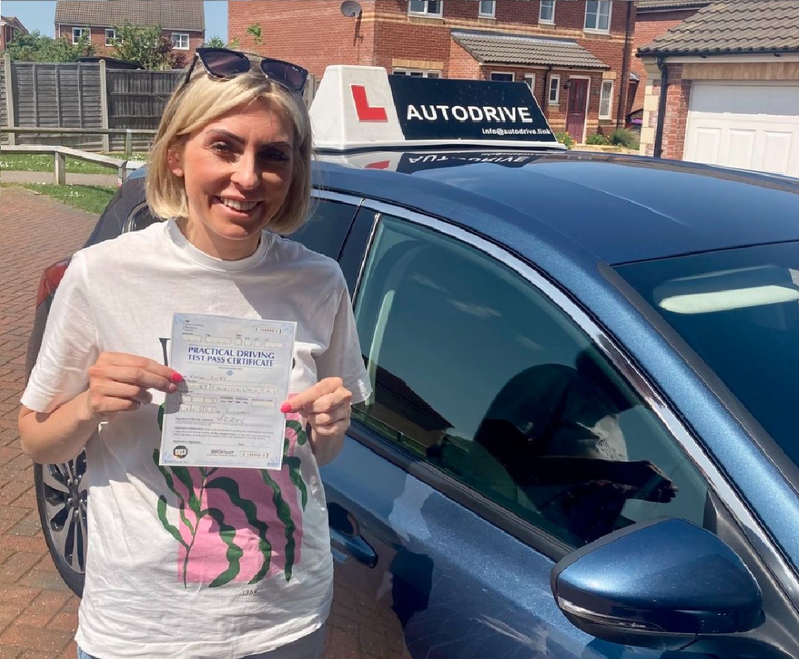 Katie E. holding her practical driving test pass certificate