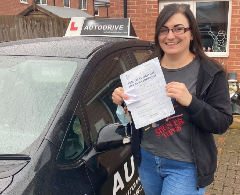 Stacey S. holding her practical driving test pass certificate